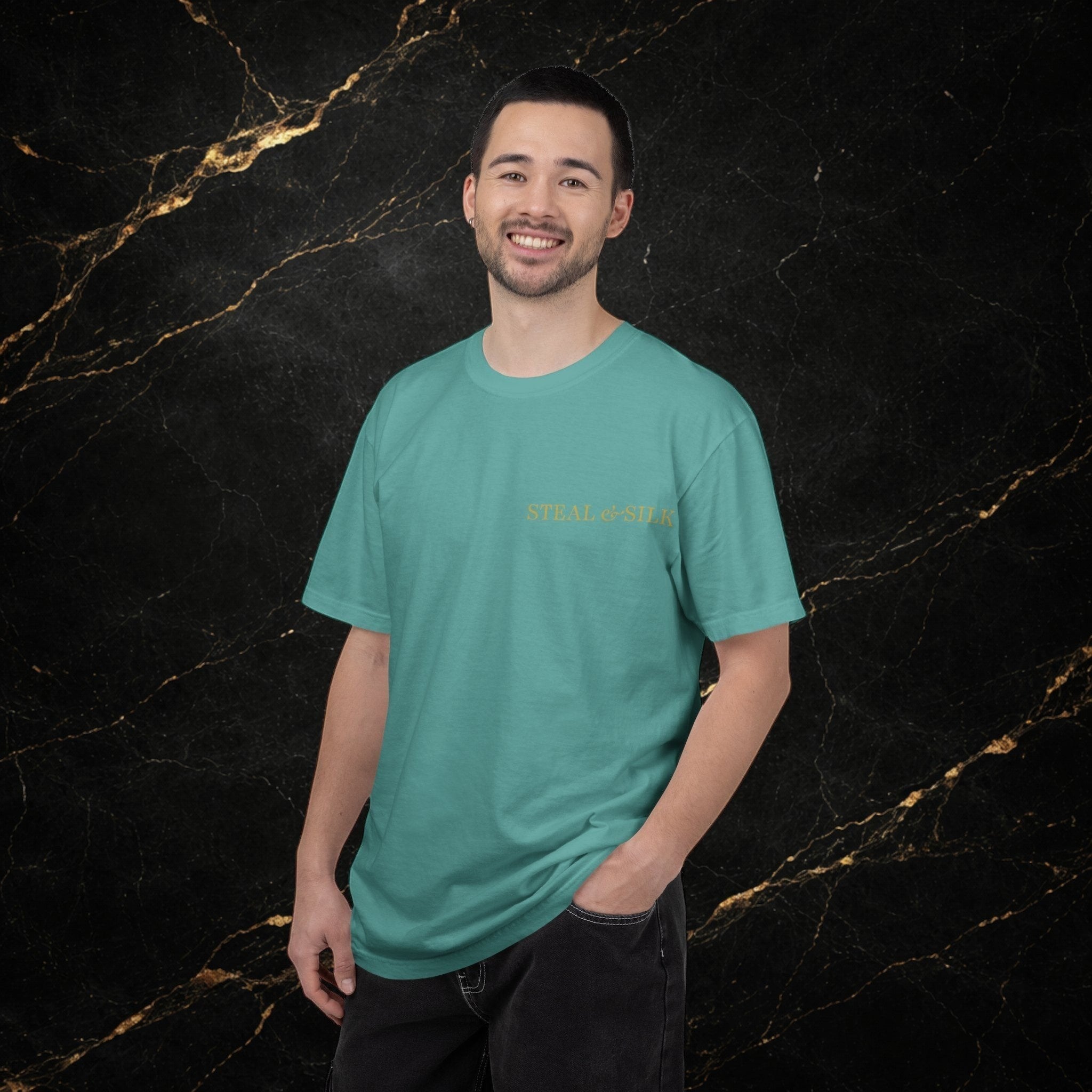 Steal & Silk teal cotton t-shirt with gold "Handle With Force" heart graphic on chest. Model wearing casual fit.